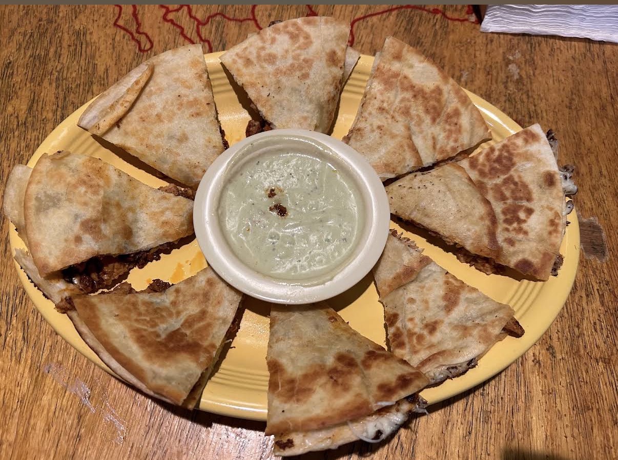 Quesadilla platter sliced into wedges with creamy dipping sauce